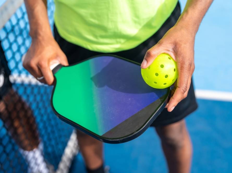 Mann hält Pickleball-Schläger und Ball in der Hand