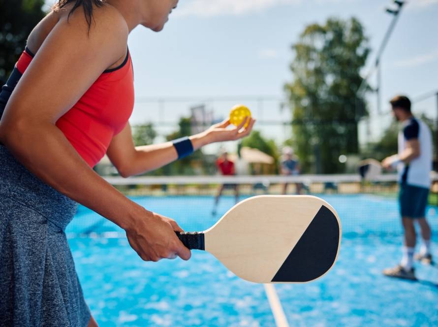 Frau serviert bei einem Pickleball-Doppel