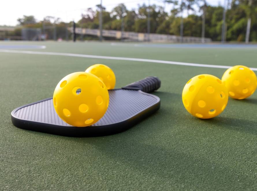 Pickleball-Bälle liegen auf einem Schläger