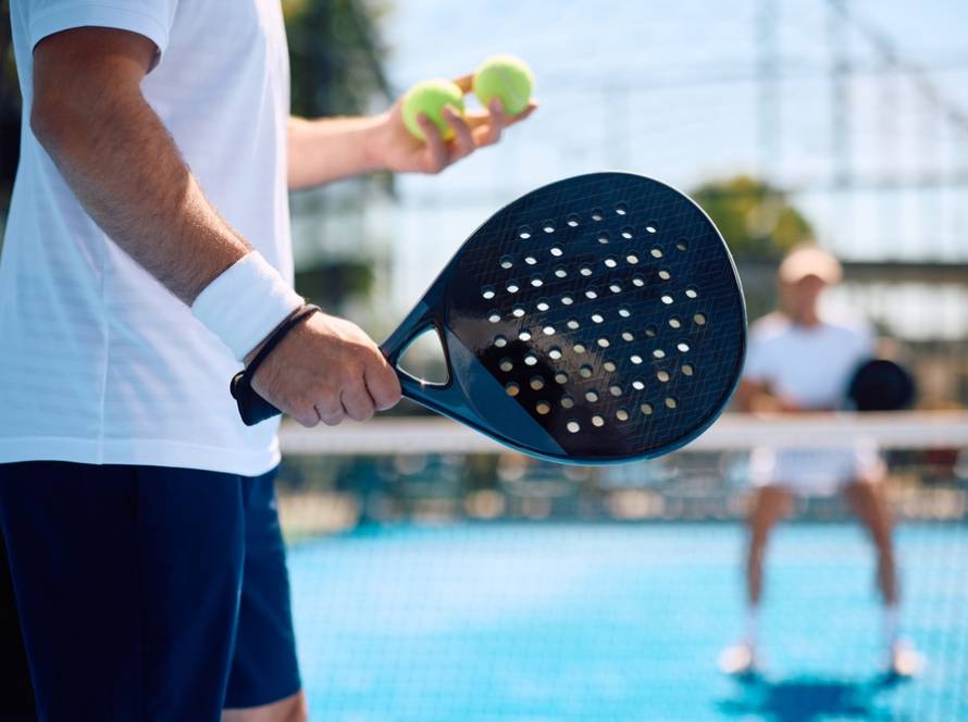 Padelspieler mit zwei Bällen in der Hand beim Aufschlag